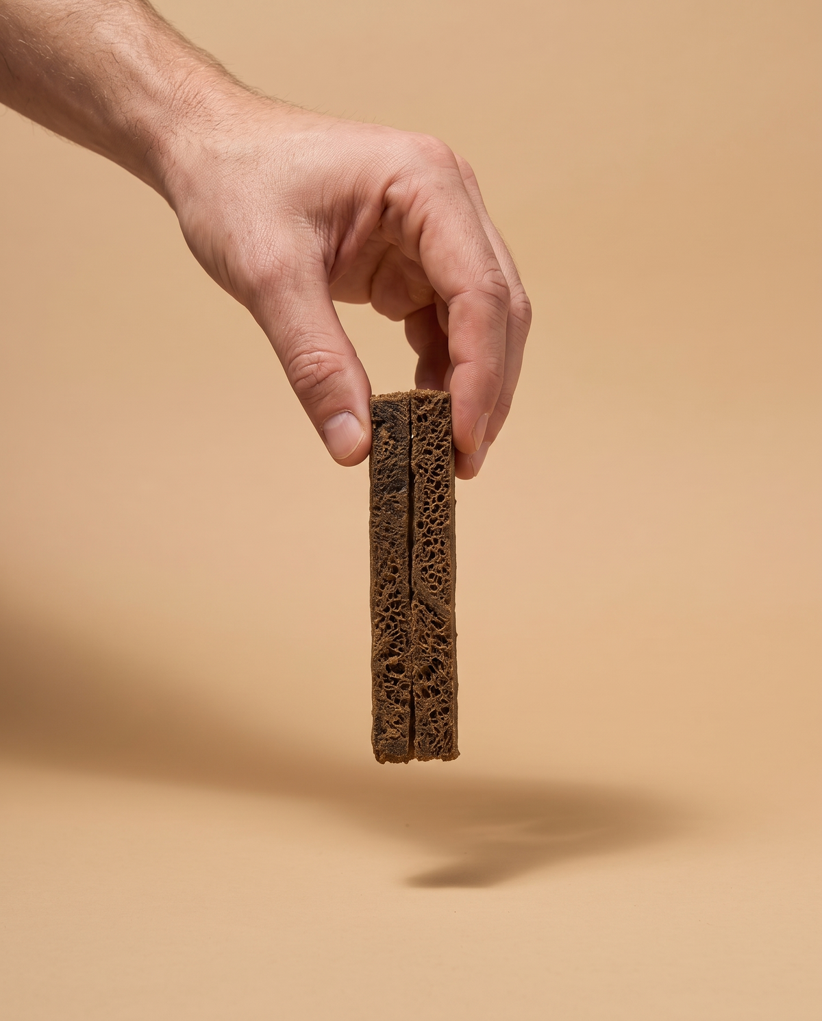 Sfeerfoto: hand biedt Take & Break met pens aan tegen een zandbeige studioachtergrond
