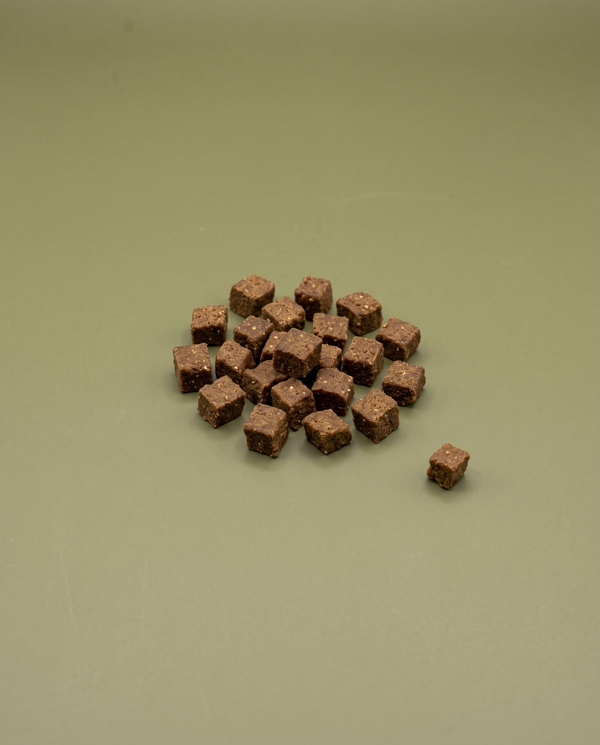 Sfeerfoto: kleine hoeveelheid mini trainers met kalkoen (200 gram), tegen een olijfgroene studioachtergrond