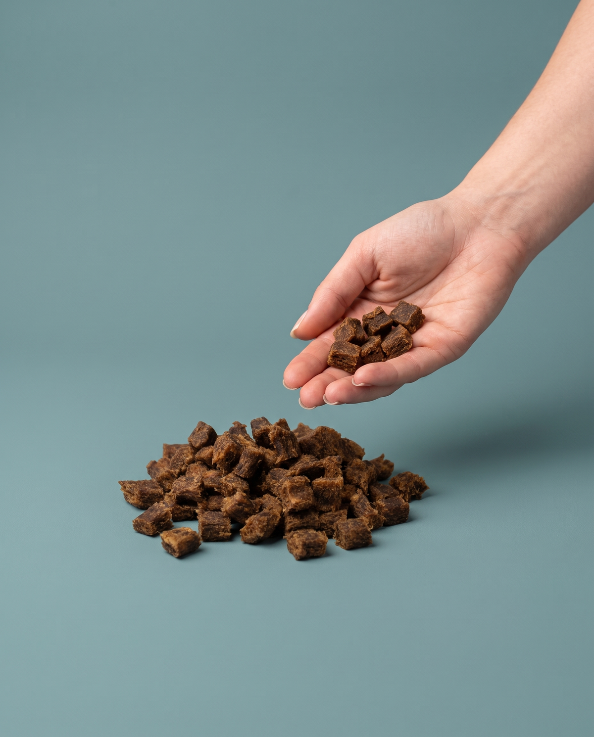 Sfeerfoto: Softies Gans (100 gram) met hand, tegen een groenblauwe studioachtergrond