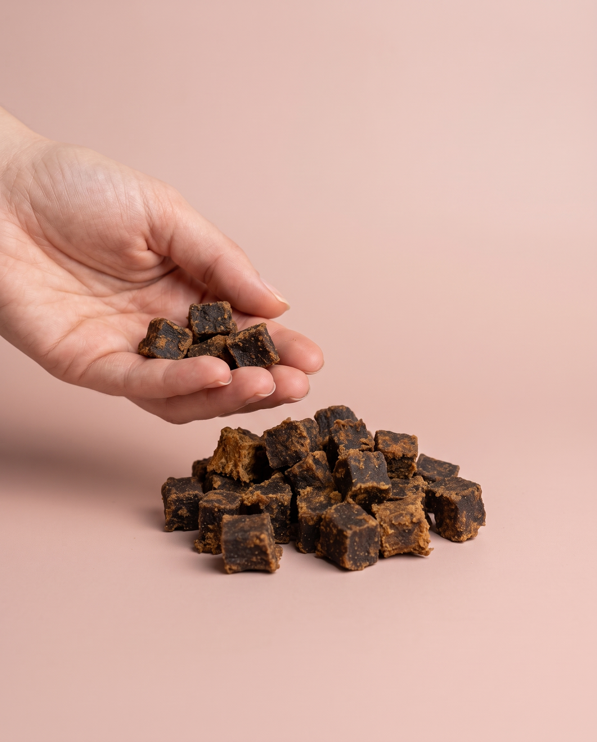 Sfeerfoto: Softies Lam (100 gram) met hand, tegen een zachtroze studioachtergrond
